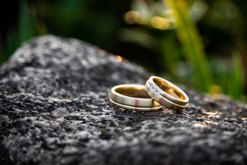 Paar goldene Eheringe auf schwarzem Stein liegend