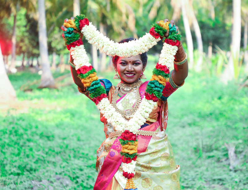 Indische Frau die indische Blumenhalskette hochhält